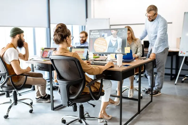 Einblick ins Büro von Sofinity in Landsberg am Lech – Frau arbeitet im Vordergrund konzentriert am Computer, das Team im Hintergrund ebenfalls vertieft in digitale Projekte